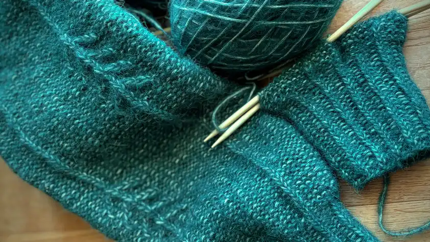 Angefangene Ärmel eines Strickpullovers
