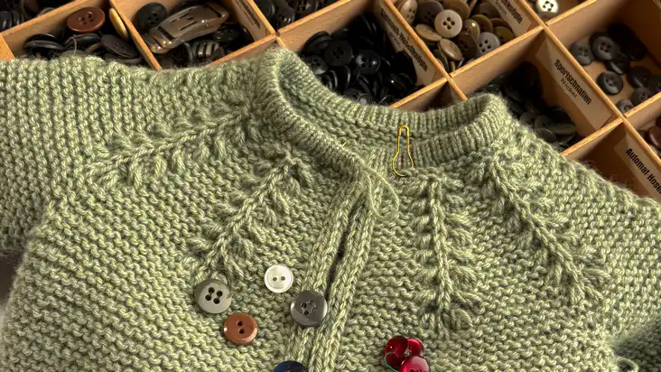Strickstrampler in Arbeit mit Knöpfen zum Annähen